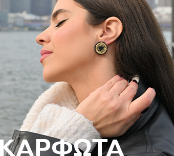 Γυναίκα με μακριά μαλλιά φορά εντυπωσιακά καρφωτά σκουλαρίκια με μοντέρνο σχέδιο,με φόντο εξωτερικό χώρο δίπλα στο νερό, δείχνοντας ιδεές για ένα ξεχωριστό δώρο.